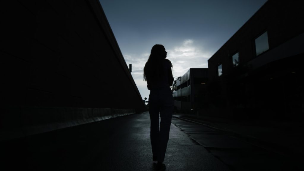 silhouette of woman walking on sidewalk during night time
