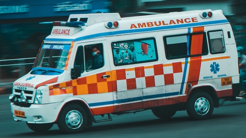 an ambulance driving down a street next to tall buildings