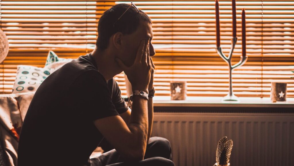 man sitting on chair covering his eyes