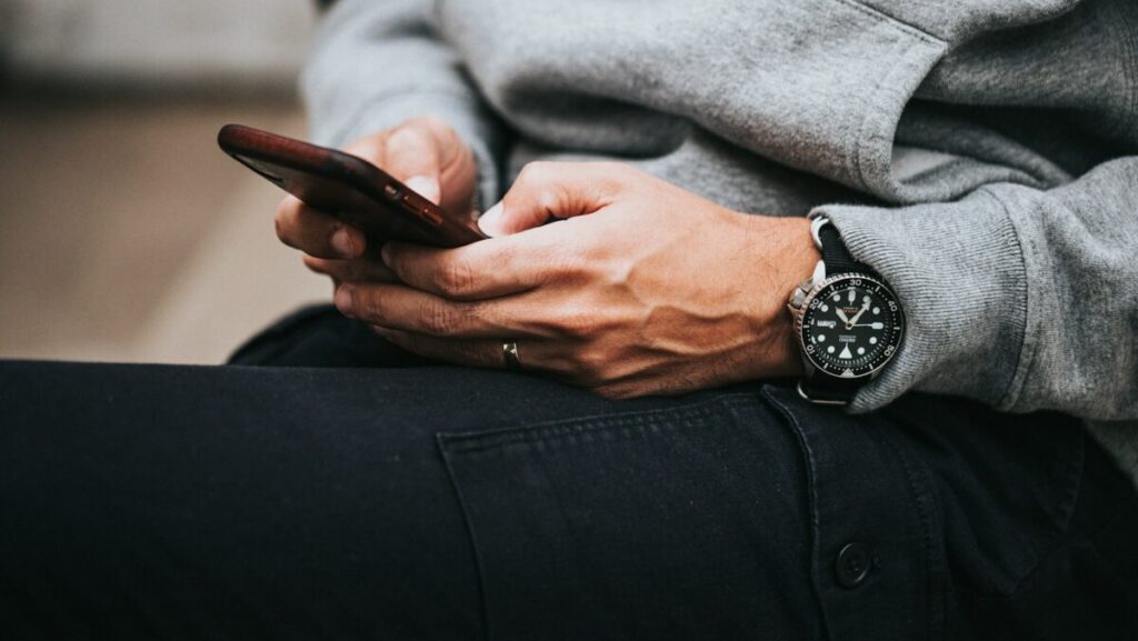 person in gray sweater wearing black and silver chronograph watch