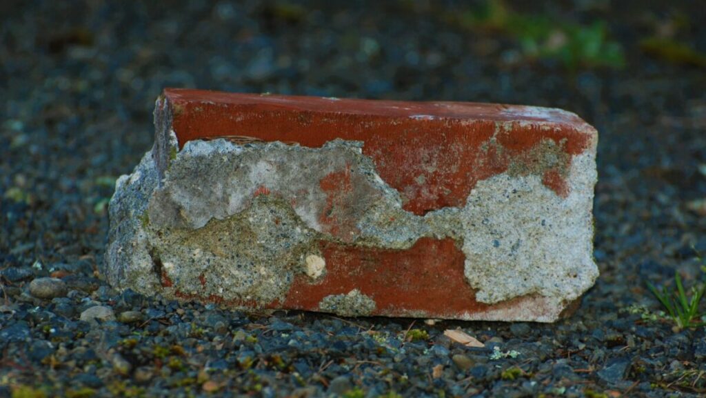 a red and white brick sitting on top of a gravel field