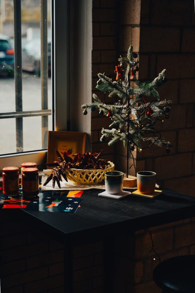 A small christmas tree sits on a table in front of a window