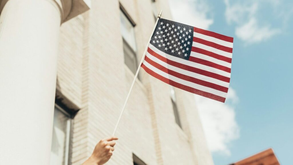 a person holding an american flag in front of a building